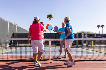 Pickleball Senior Citizen Touch paddles at center court 