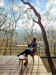 40-year-old divorced single Latino adult woman is sitting on the terrace of her cabin in the middle...