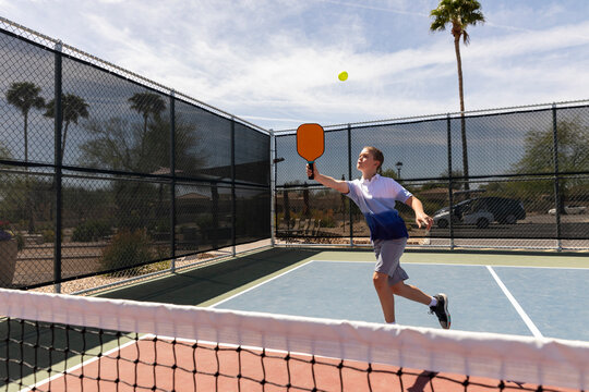 Young boy Pickleball match player looks to swing at ball 