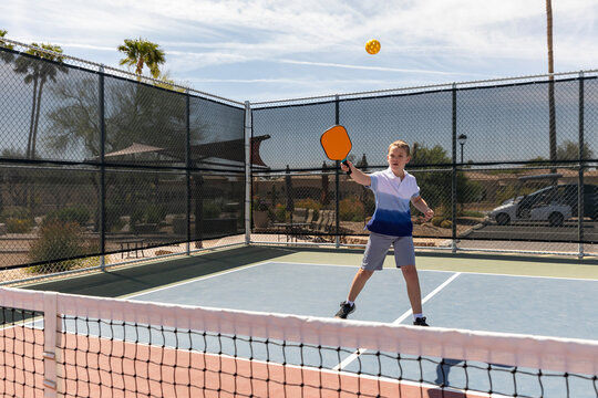 Young boy Pickleball player looks to swing at ball 