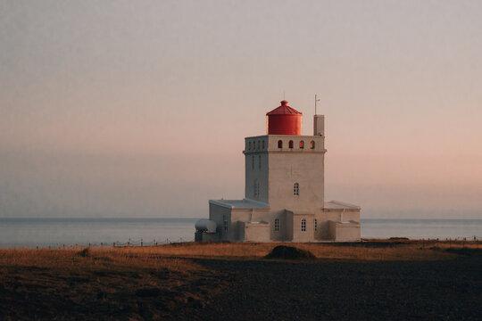 picturesque lighthouse is illuminated by the pink light of a sunset 