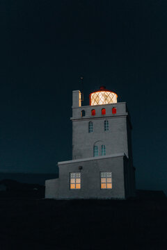 lighthouse stands against dark nighttime sky casting beam of light