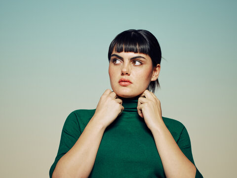 Woman with mistrust expression looking to the side touching her neck