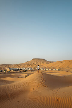 Adventurous man walking through the desert dunes