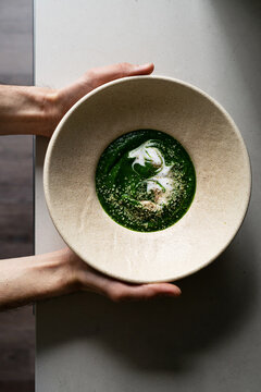 Hands holding freshly cooked organic nettle tops cream soup