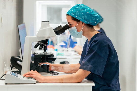 Biologist in uniform working using microscope