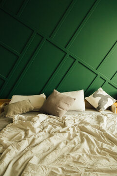 Pillows on Messy Bed with Green Bedroom Wall