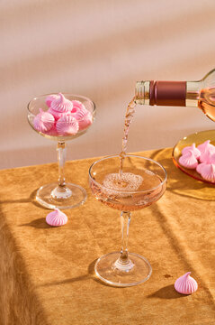 pouring glass of rose wine and pink meringues