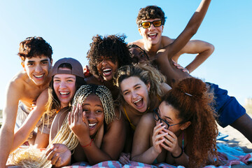 Happy diverse friends hugging on beach