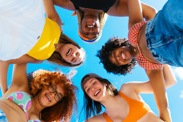 Happy diverse women hugging each other on blue sky