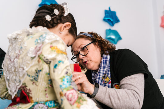 Woman dressing up girl for Las Fallas