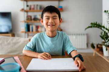 Boy smiling while doing homework at home.
