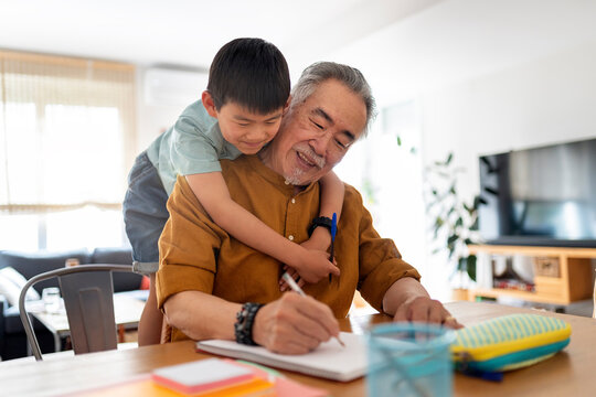 Elderly Chinese man helps grandson learn.