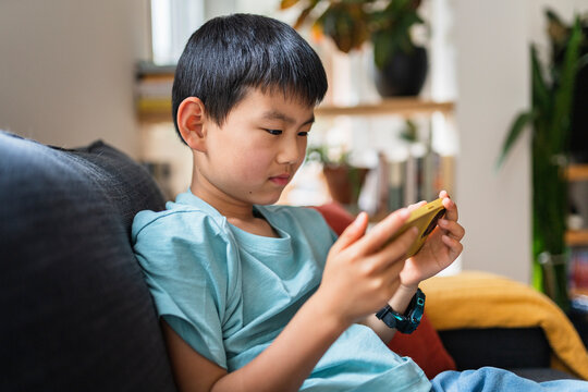 Serious Chinese boy playing mobile game.