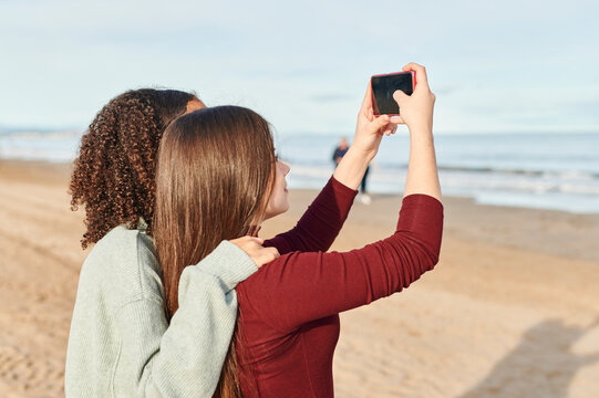 Teen girls taking selfies on a beach