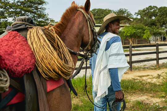 A young farmer is pulling his horse back to the stable