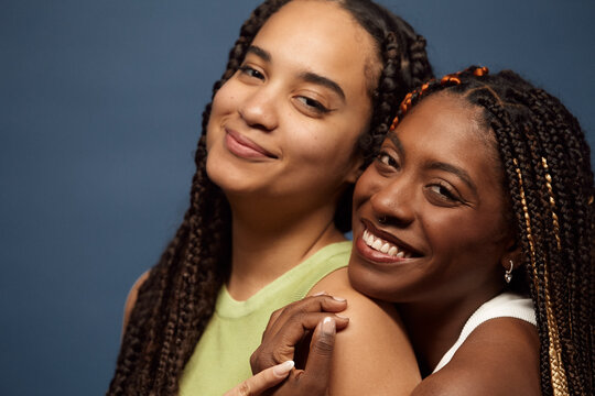 Close-up of two happy friends with long braids.