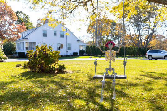 Lone Halloween Skeleton decoration on swing in neighborhood in fall 