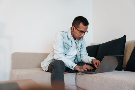 Side view of a tattooed man working on his latop