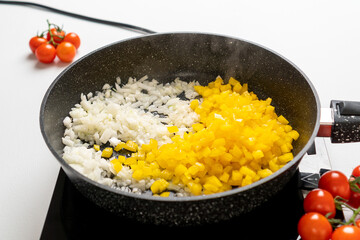 A frying pan with Chopped Bell Peppers and Onions is fried on the Stove. Recipe and cooking process for Shakshuka and Menemen. Step by step. Third photo