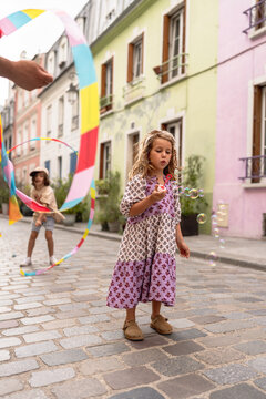 Little girl blowing bubble in the street