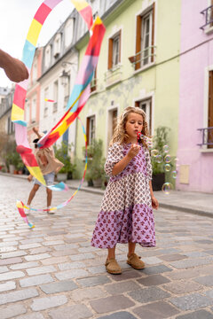 Little girl blowing bubble in the street