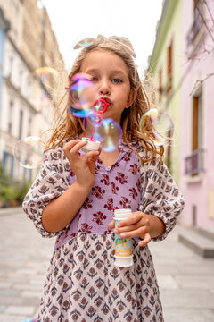 Little girl blowing bubble in the street