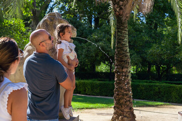 Happy family playing with a fountain at park 
