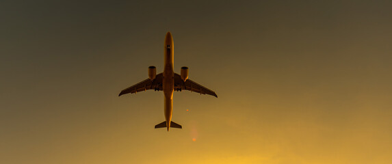 Bottom view of a flying plane at sunset. Widescreen. 