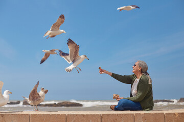 At Essaouira beach, an elderly tourist kindly feeds the local wildlife