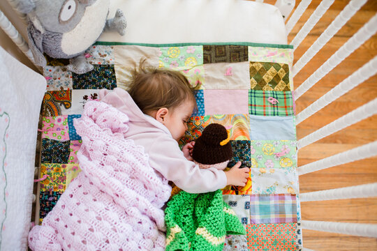 Overhead view of child sleeping in crib