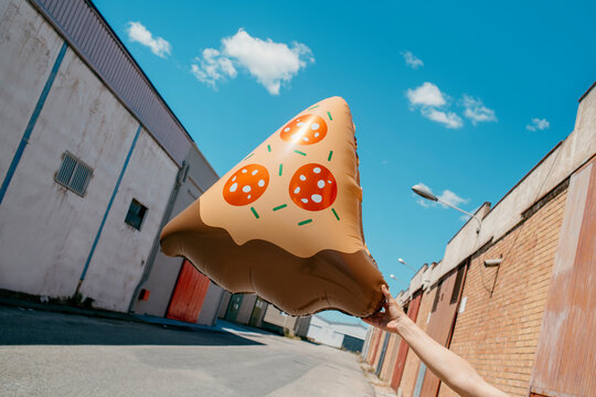 man holds a balloon in the shape of a slice of pizza 