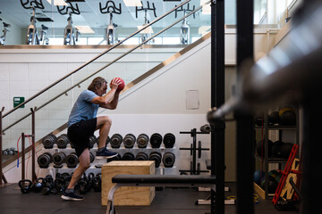 Man with heavy ball stepping up onto box