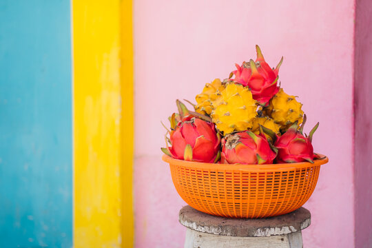 Basket of dragon fruit in front of a pink wall