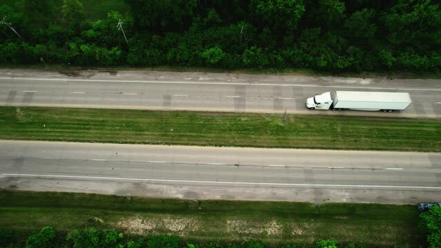 unique aerial of a semi truck and trailer turning left sorounded by green foliage.  Cinematic aerial, Wisconsin USA 4k