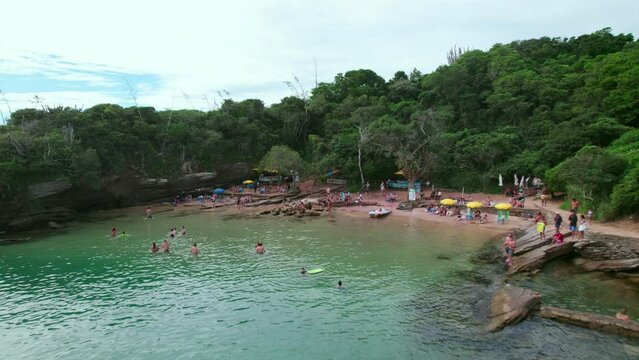 Flyover dolly out of people enjoying Azeda and Azedinha beaches, B&uacute;zios, Brazil tourist boats in pristine waters with a couple kayaking