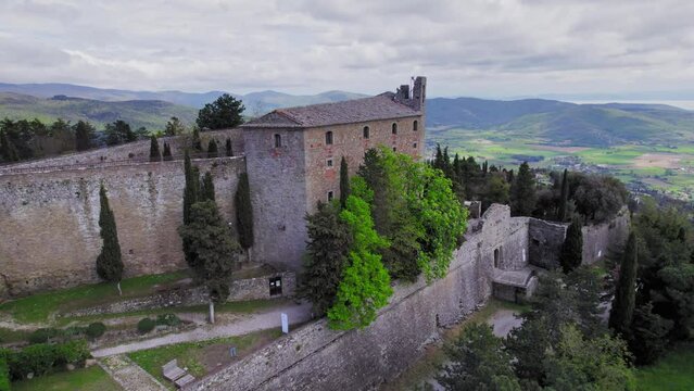 Fortress of Girifalco on hill in rural Tuscany, forward rising aerial
