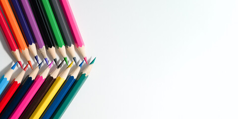 Colored pencils lying over paper, flat lay.