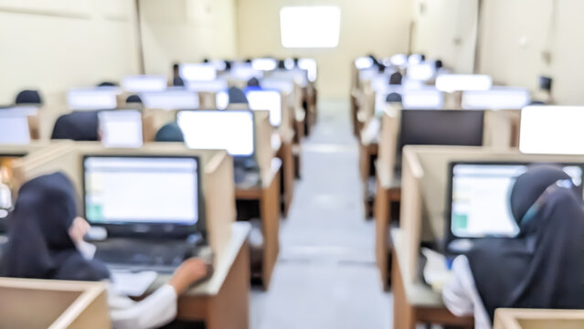 Blurred image of amount of students working on a computer-based competency test in the Computer Classroom. Industry Revolution 4.0 Concept