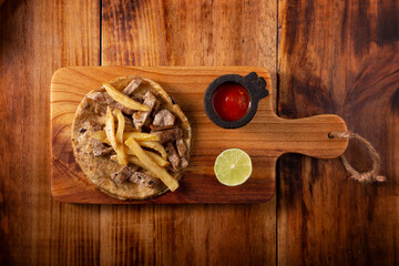 Beef steak taco with french fries. Very popular taco in Mexico called Taco de Bistec or Carne Asada, homemade roast beef served on a corn tortilla. Mexican street food. Topview.