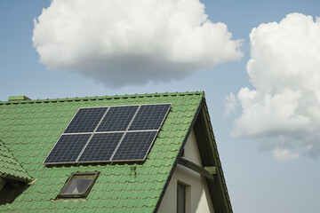 Fototapeta premium Solar panels on the roof of the modern house. Residential house cottage with blue shiny solar photo voltaic panels system on roof. Renewable ecological green energy production concept. Sustainable.