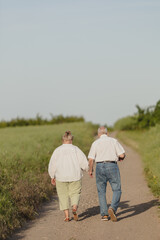 Naklejka na ściany i meble elderly couple walking in nature , people behind