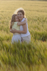 Fototapeta na wymiar two pre-teen girls happy hugging in a field of rye in nature