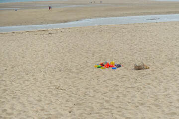 Fototapeta na wymiar Jouets de plage colorés posés sur le sable, à marée basse