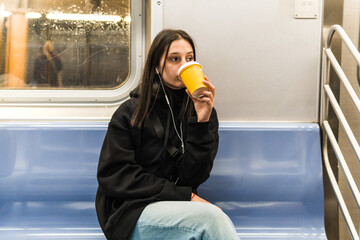 young woman drinking coffee in the subway