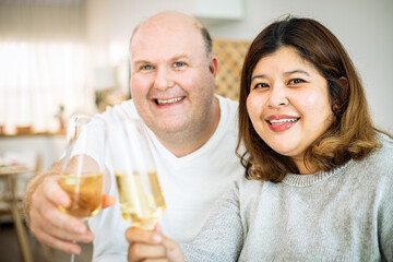 Happy senior couple in love hugging, laughing, drinking wine, enjoying talking, having fun together celebrating Valentines day dining at home