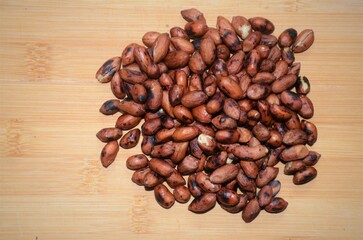 Roasted Peeled peanuts (Arachis hypogaea) on a wooden brown background. isolated. The view from top. Space for text.