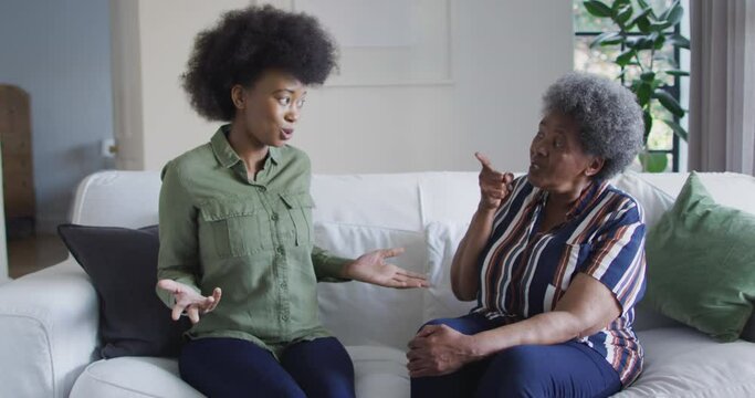 Sad african american adult daughter and senior mother having disagreement at home, slow motion