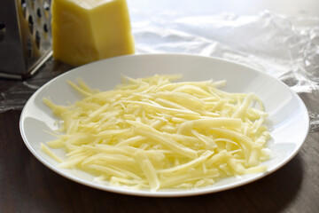 Grated cheese on a white plate.  Cooking food preparation concept. 