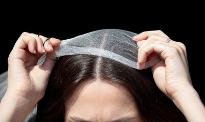 Naklejka premium The girl puts a veil on her head on a black background